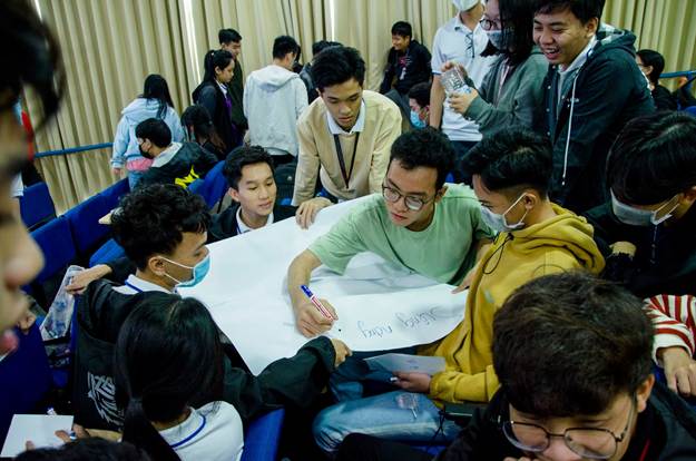 A group of people sitting around a large piece of paper

AI-generated content may be incorrect.